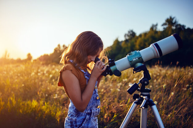 Ein Mädchen schaut durch das Teleskop um das Universum zu erkunden.