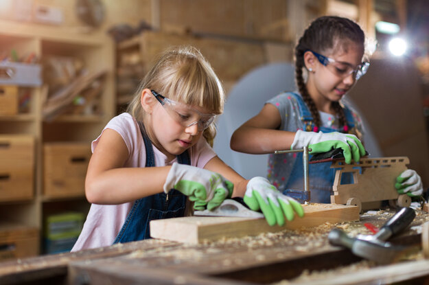 Zwei Mädchen arbeiten mit Holz und schleifen es.