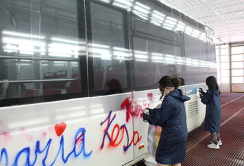 Schülerinnen bemalen IVB Bus mit Spraydosen